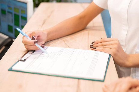 Professionnelle de la santé remplissant un formulaire médical sur un clipboard.