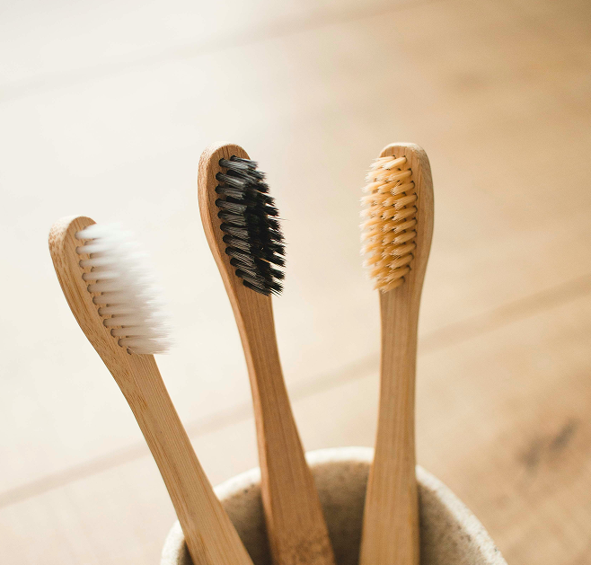 Trois brosses à dents en bambou aux poils de différentes couleurs.